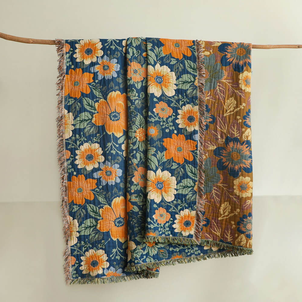 Blue daisy floral cotton throw blanket hanging on a wooden rod with fringe edges
