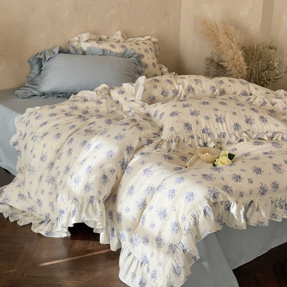 Full view: Blue rose floral duvet cover and pillowcases with ruffles, over a light blue sheet.