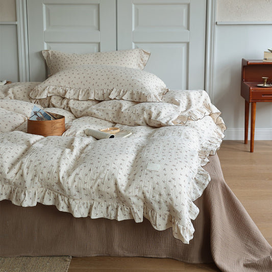 Close-up of a Cottagecore floral muslin duvet cover set with ruffles and a textured brown bed skirt, featuring a cozy bed scene with a wooden box.