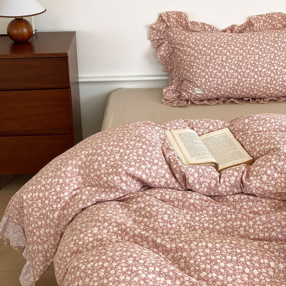 Close-up of the pink ditsy floral duvet and pillow, with a book resting on the cozy cotton muslin fabric.