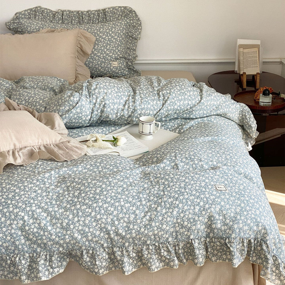 Angled view of the blue ditsy floral bedding set, showing the crumpled texture of the cotton muslin fabric and the delicate ruffle trim.