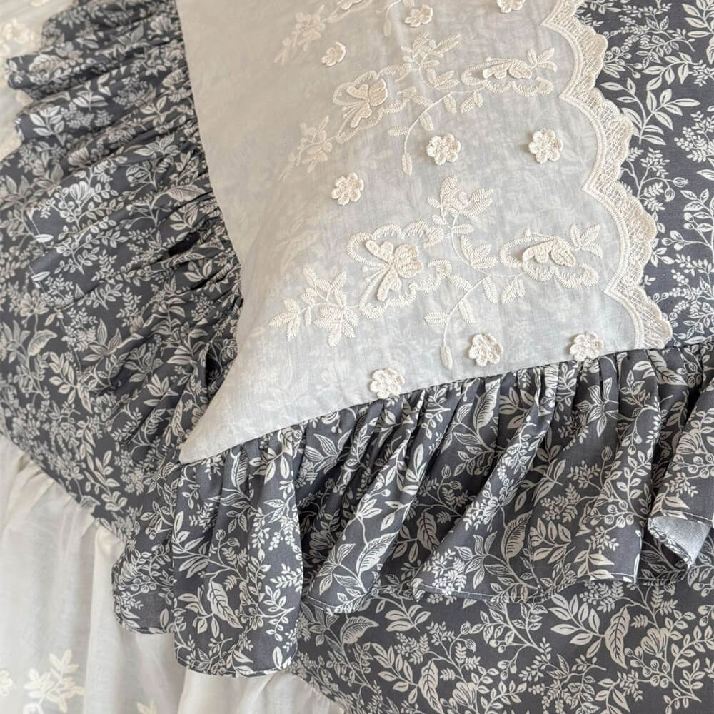 Close-up of embroidered ivory pillow panel with gray botanical ruffle trim