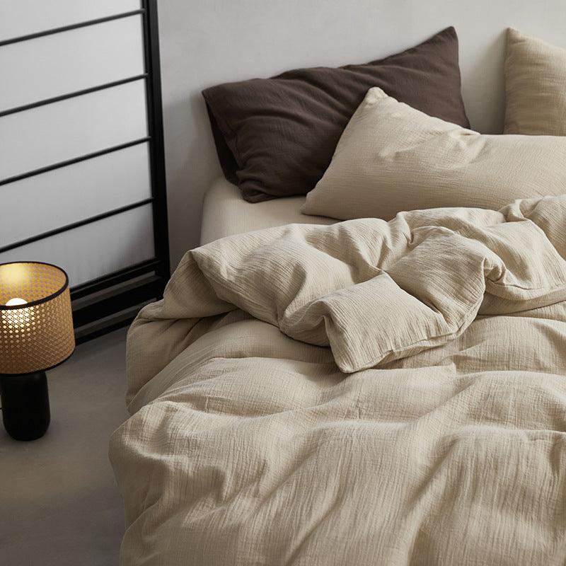 Neatly made bed with beige bedding and pillows, next to a bedside lamp.