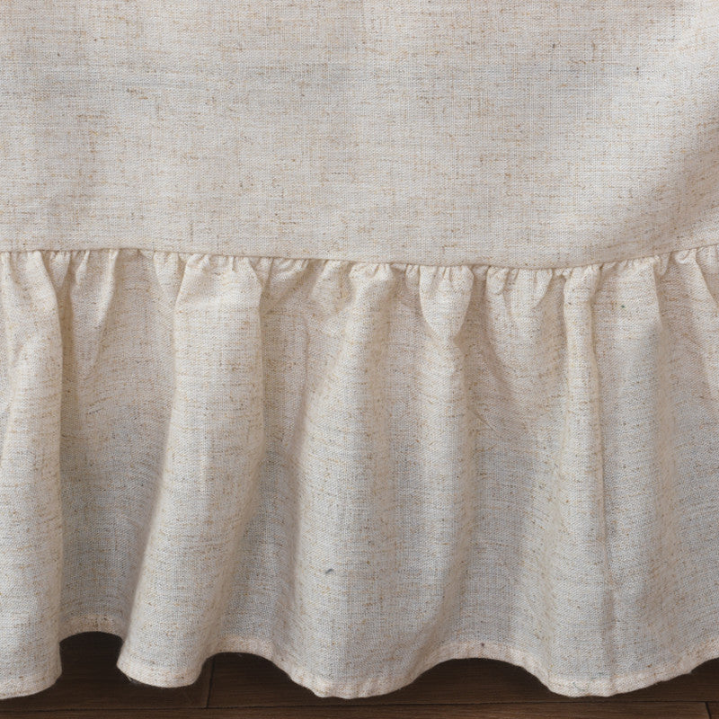 A detailed view of the bottom hem of the beige sofa cover, showcasing the delicate ruffles and the linen-like texture of the fabric.