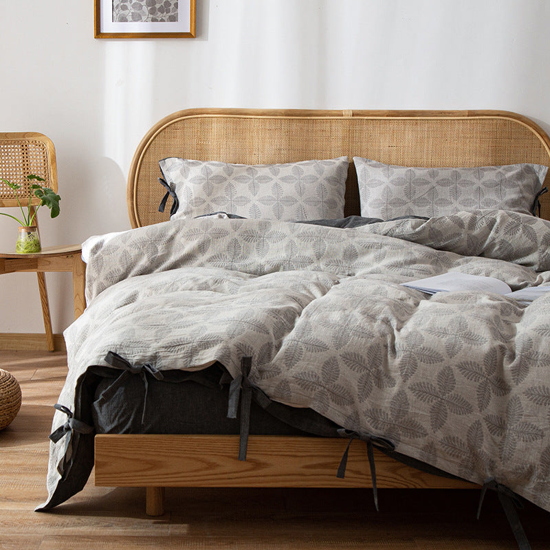 Cozy Queen Size Bedding Set with light grey jacquard leaf pattern and tie closure on wooden bed.