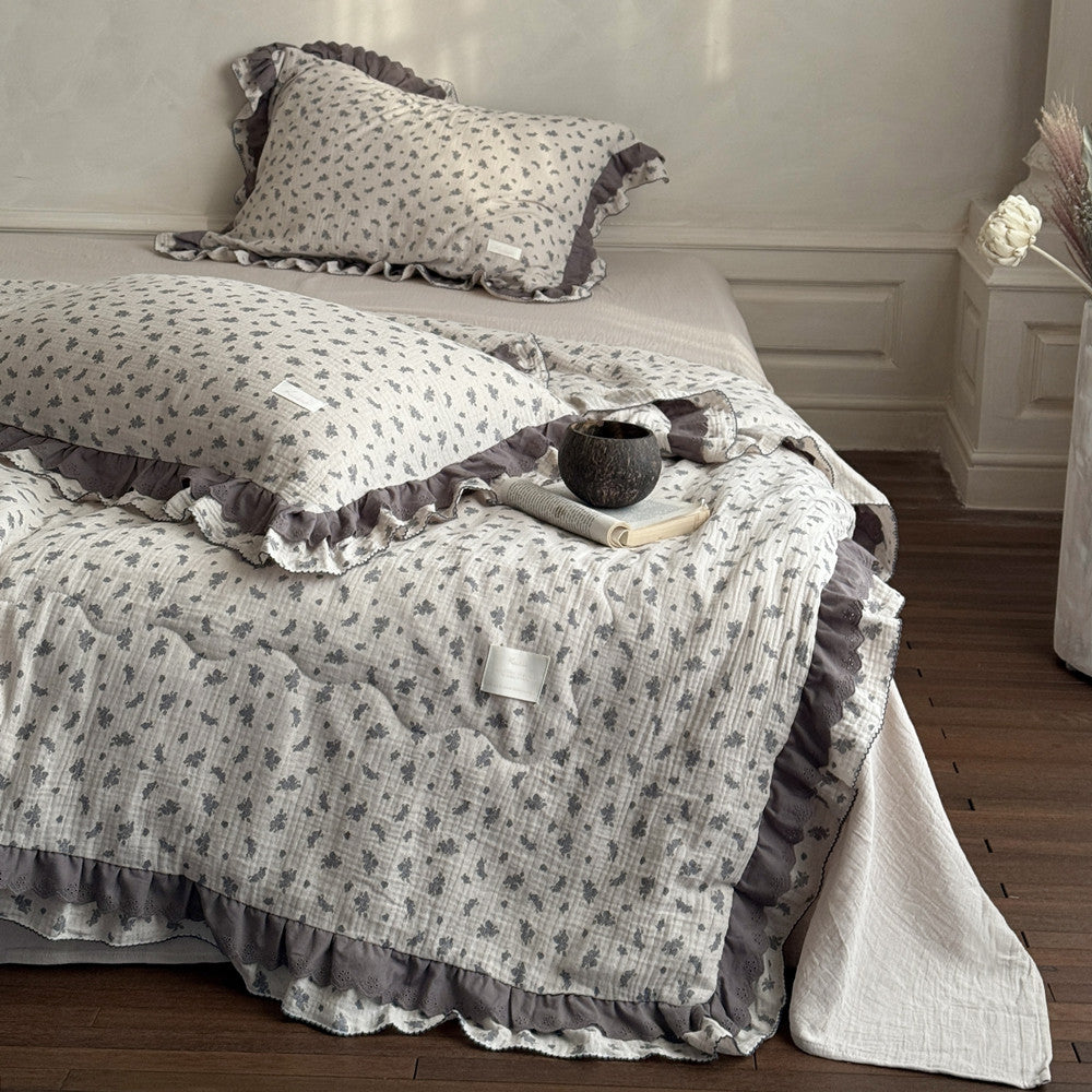 Bed with floral-patterned comforter and pillows in a bedroom setting.