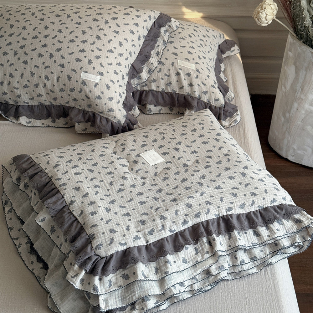 Floral-patterned quilt with ruffled edges on a bed in a bedroom setting.