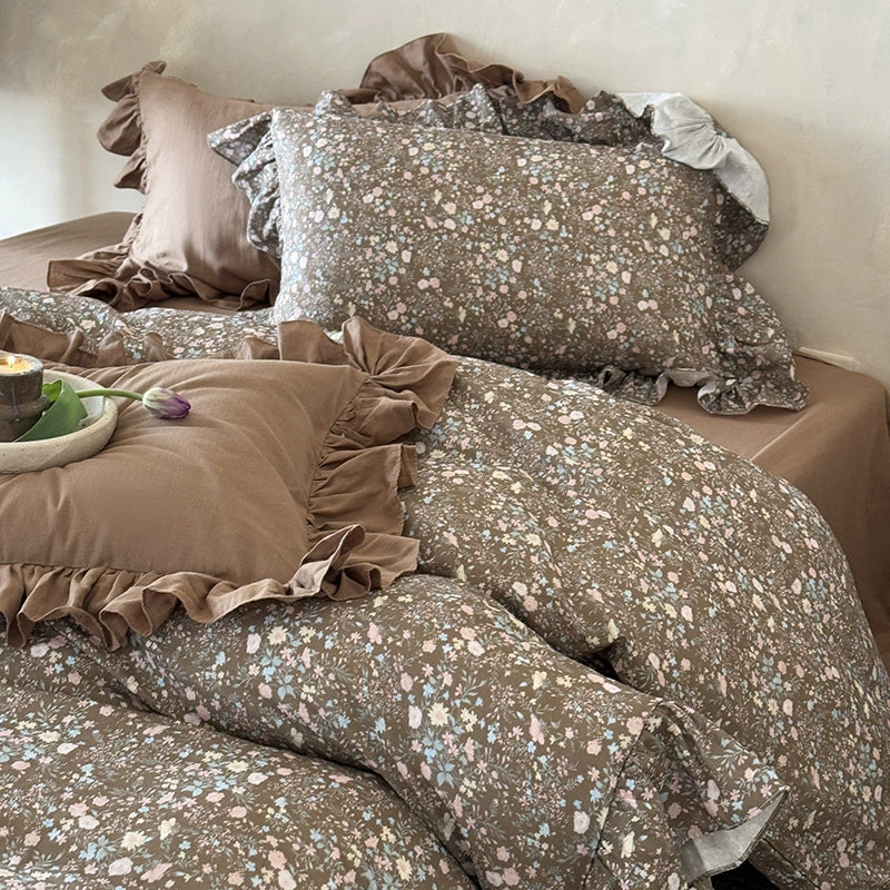 Full bed shot showcasing the relaxed drape of the ruffled cotton muslin duvet and the overall earthy floral theme of the set.