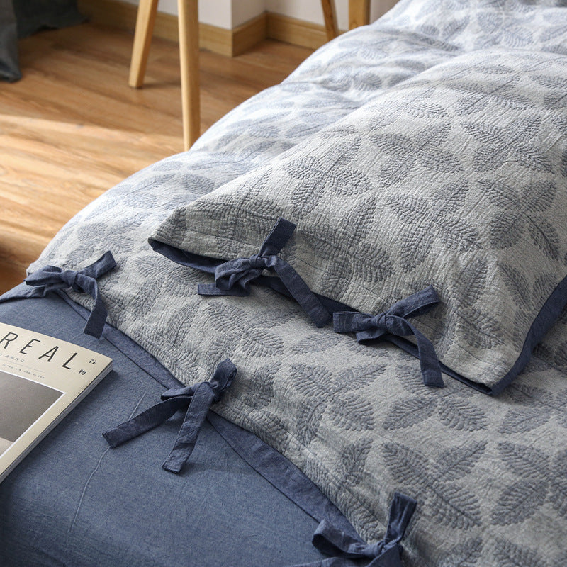 Detailed view of Jacquard Duvet Cover and pillow sham, highlighting the woven leaf texture and dark blue tie closures.