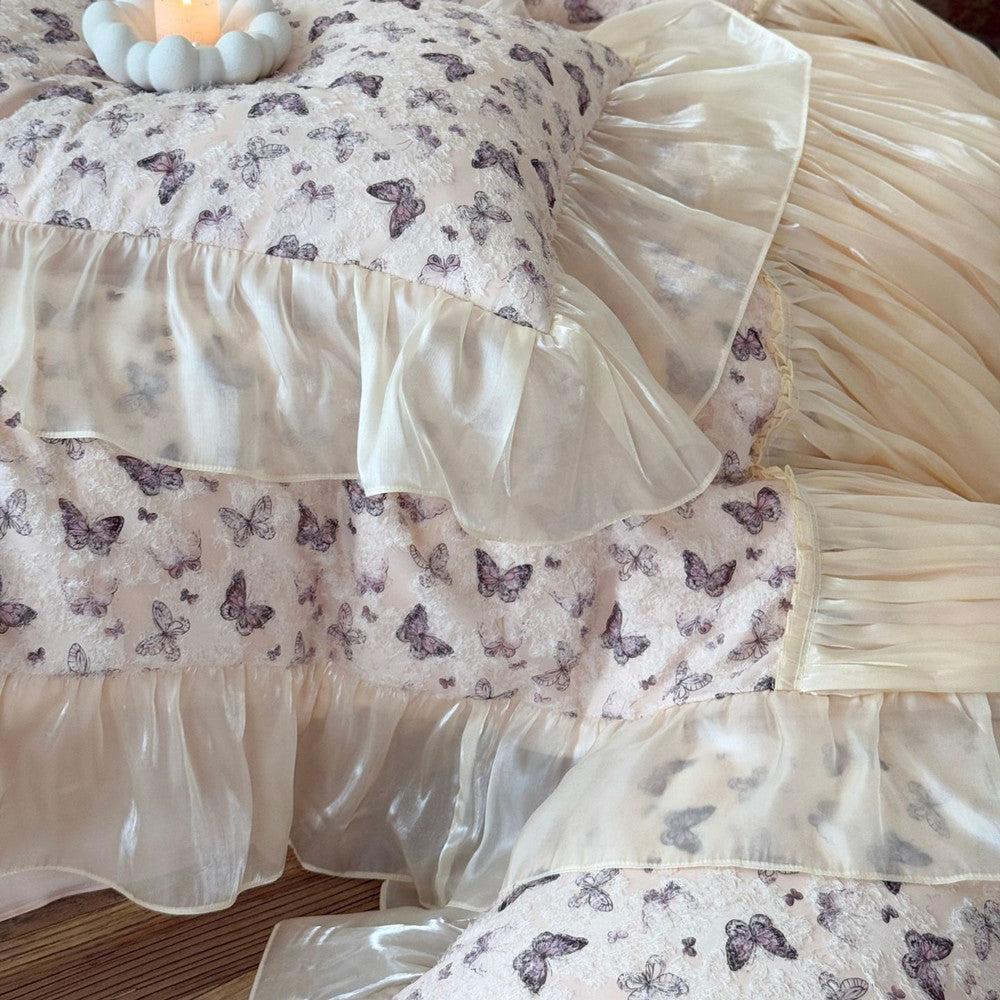 Butterfly-patterned bedding with ruffled layers on a bed.