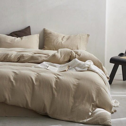 Beige bedding set on a bed with pillows in a minimalistic room.