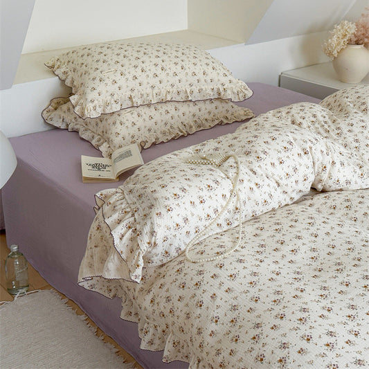 Yellow Floral Muslin Gauze Duvet Cover Set with pillows and long bolster on a purple sheet.