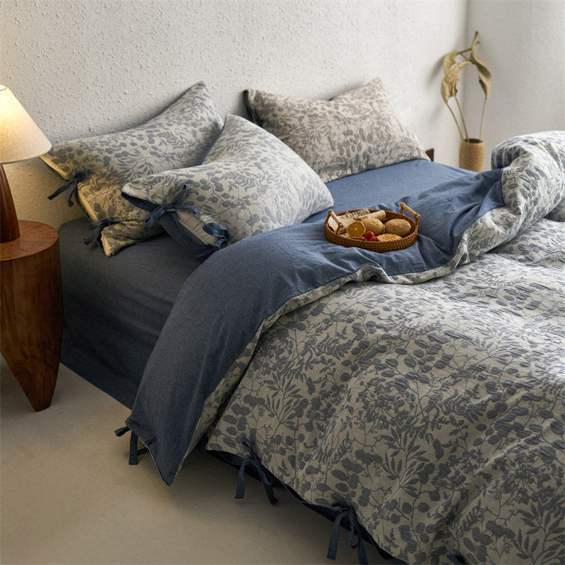 Full view of slate blue floral jacquard bedding set, reversible with solid blue side and tie closures.