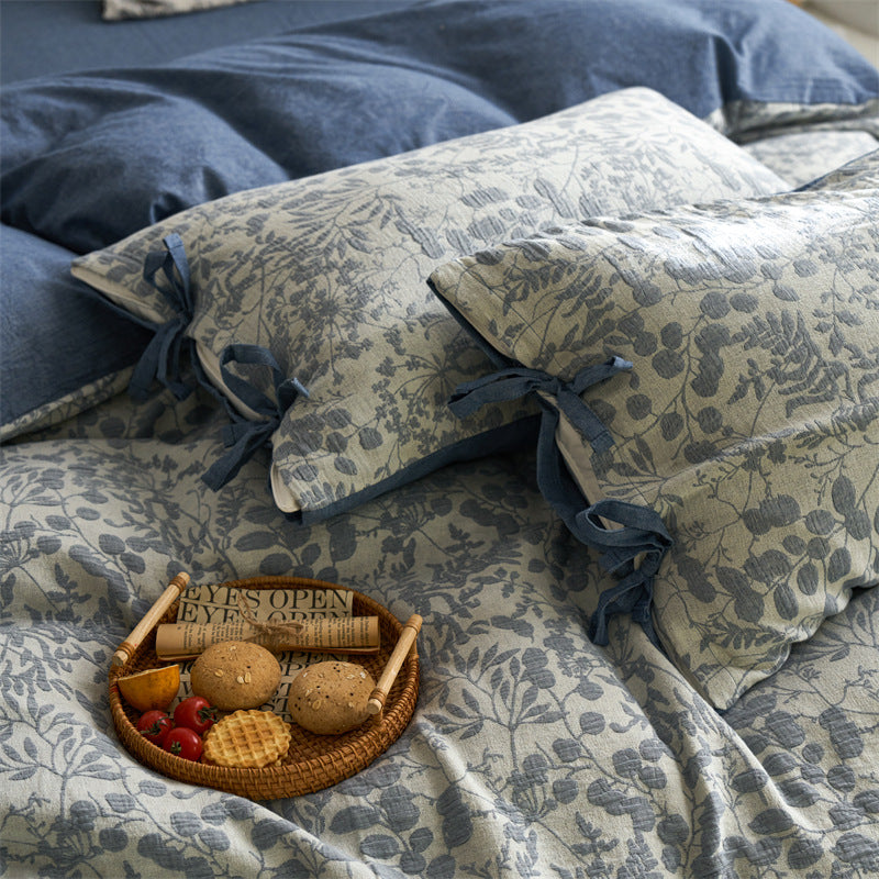 Close-up of slate blue floral jacquard pillows and duvet with tie closures and breakfast tray detail.