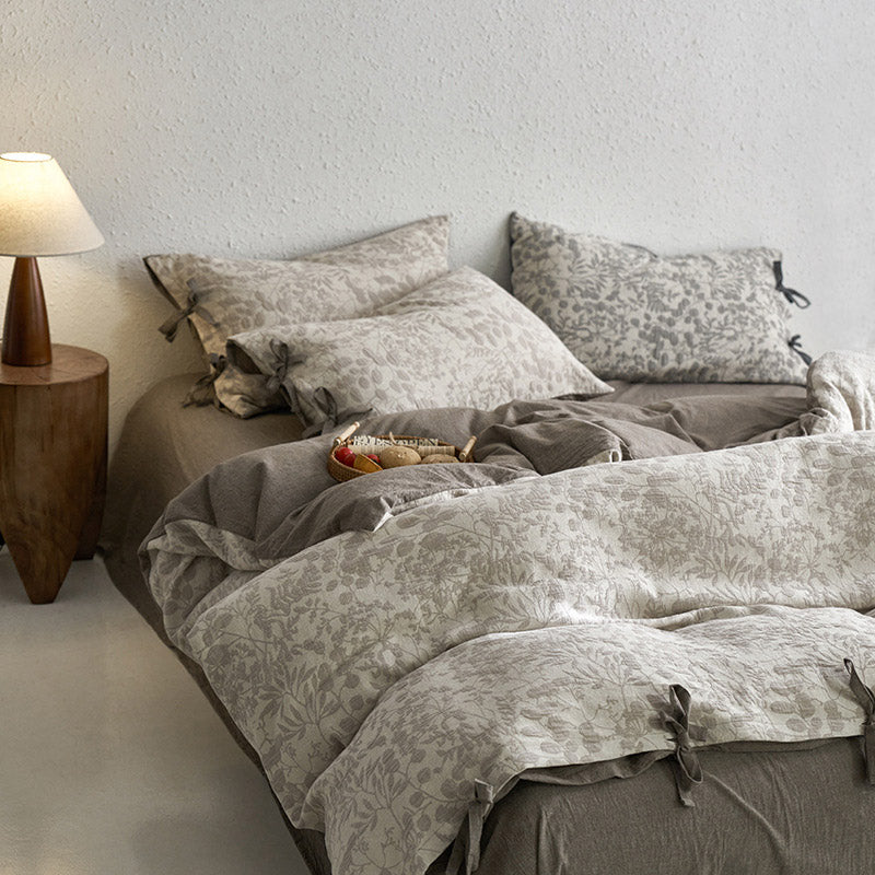 Full view of ash grey floral jacquard bedding, showing the reversible solid color side and tie closures.