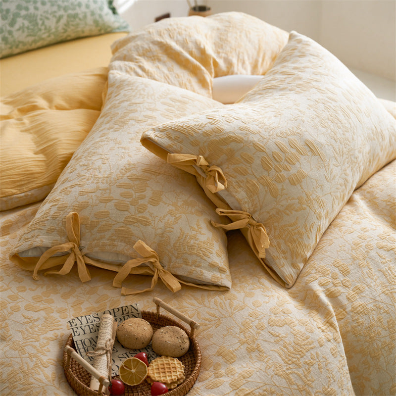 Close-up of yellow floral jacquard pillows with tie details and subtle woven texture.