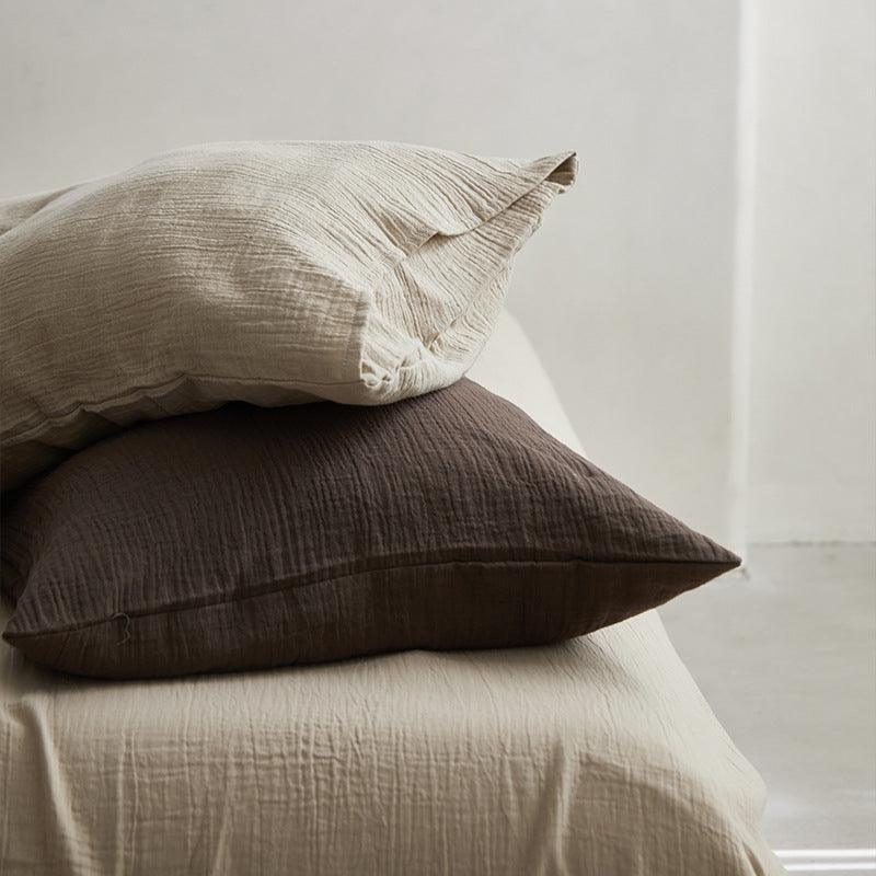 Two textured pillows stacked on a bed with a neutral background