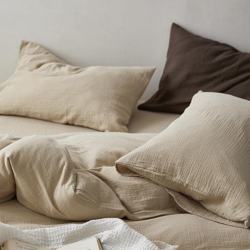 Beige bedding with pillows on a bed against a neutral wall