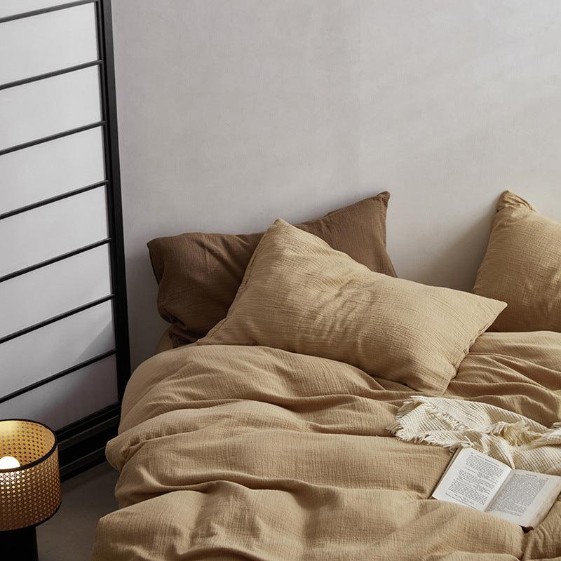 Beige bedding with pillows and a book on a bed in a bedroom setting.
