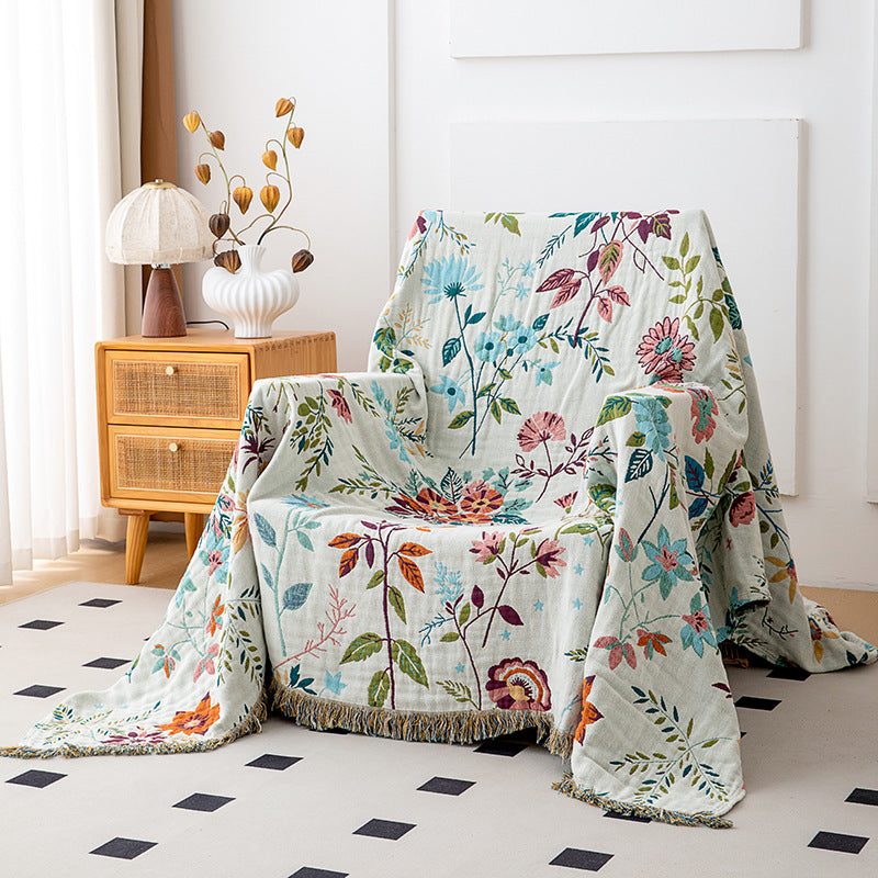 Ivory botanical cotton throw blanket with fringe styled over an accent chair