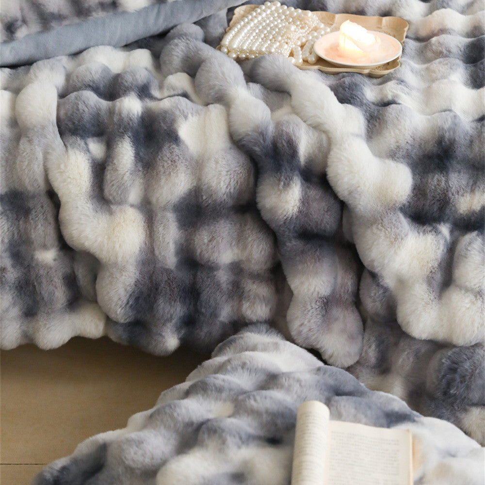 An extreme close-up of a gray and white tie-dye patterned faux rabbit fur blanket, highlighting its incredibly soft and fluffy texture.