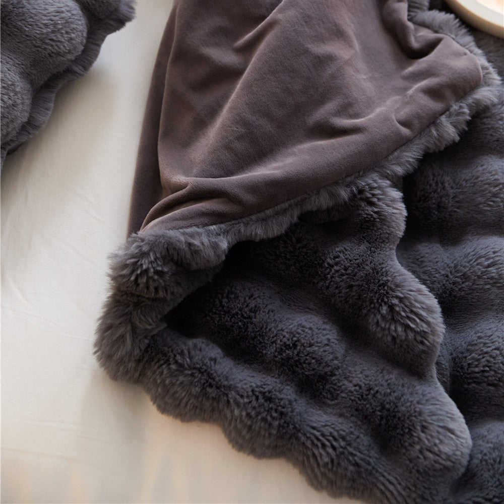 A detailed close-up of a reversible Charcoal faux rabbit fur blanket, showing both the plush bubble texture and the smooth, solid-color reverse side.