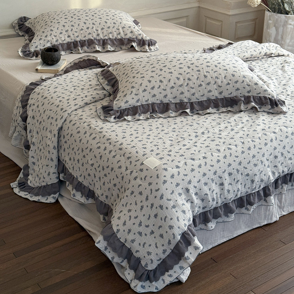 Floral patterned comforter set with ruffled edges on a bed in a bedroom.