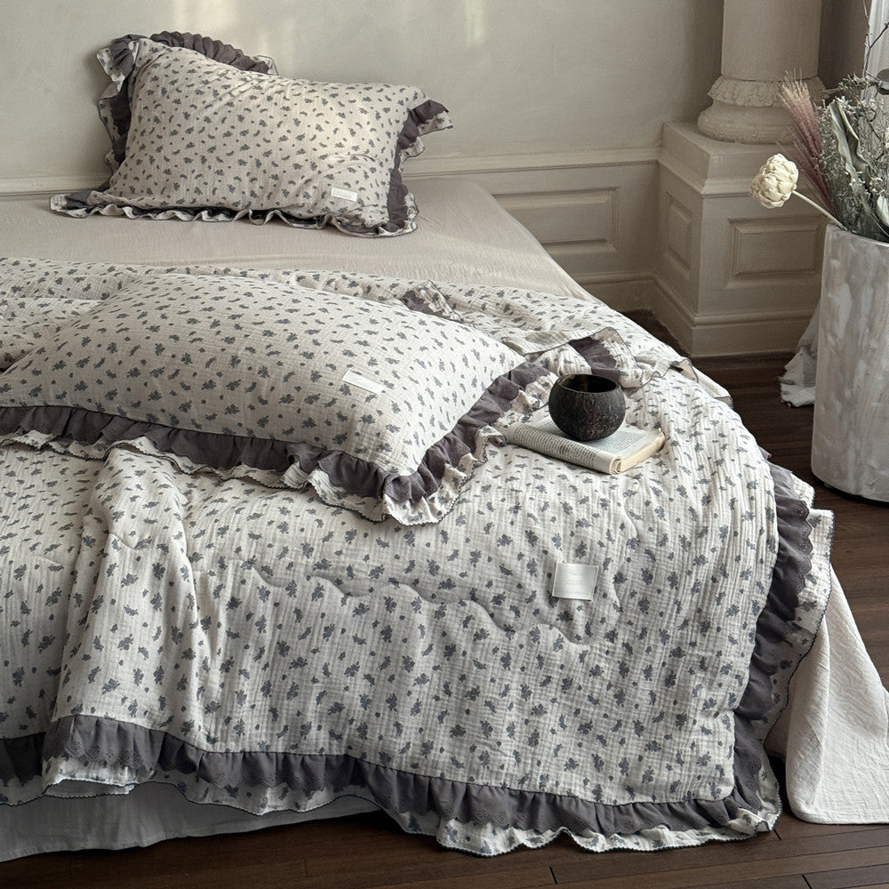 Lightweight dusty blue floral comforter with ruffled trim on a bed