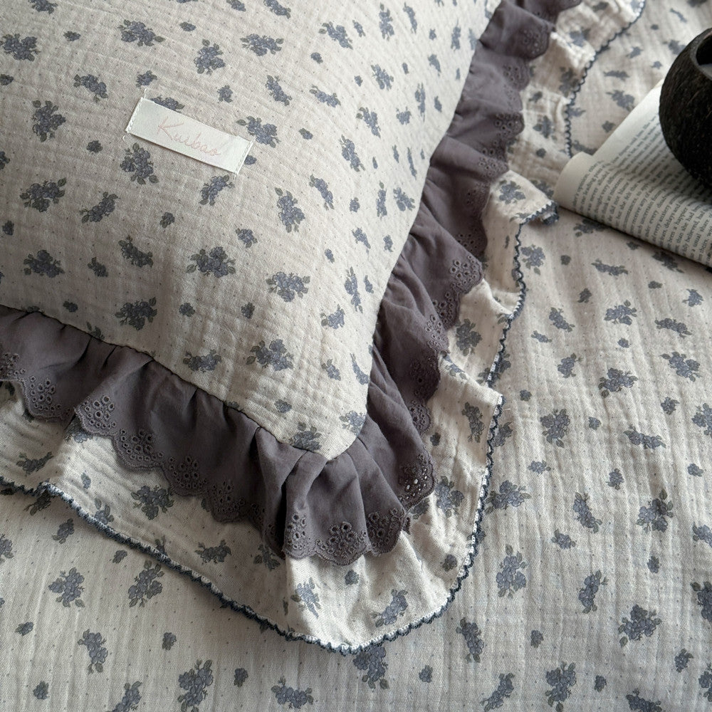 Detail view of ruffled edge and floral pattern on pillowcase and lightweight comforter