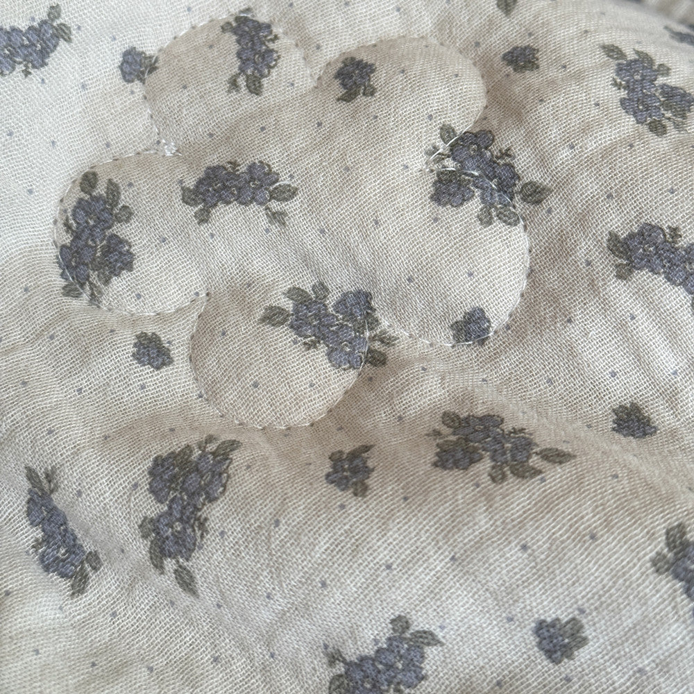 Close-up of dusty blue floral comforter with flower-shaped quilting