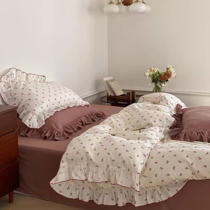 Soft cotton muslin bedding set with white cherry print duvet and matching ruffled pillow sham; features solid dusty rose sheet and accent pillows.
