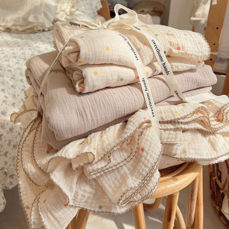 Soft cotton muslin duvet cover set with a polka dots print and a solid neutral set, folded and tied with a ribbon for gifting.