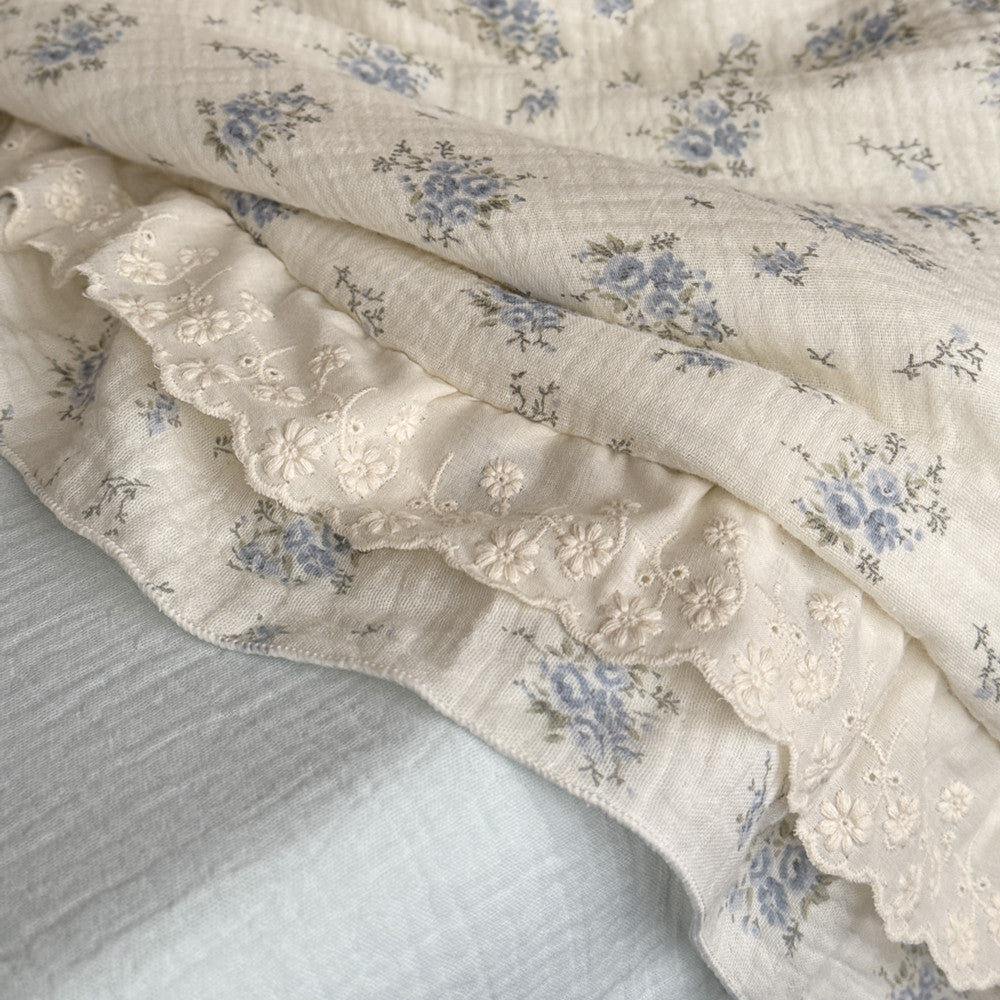 Close-up of cotton gauze comforter fabric with floral and lace edge