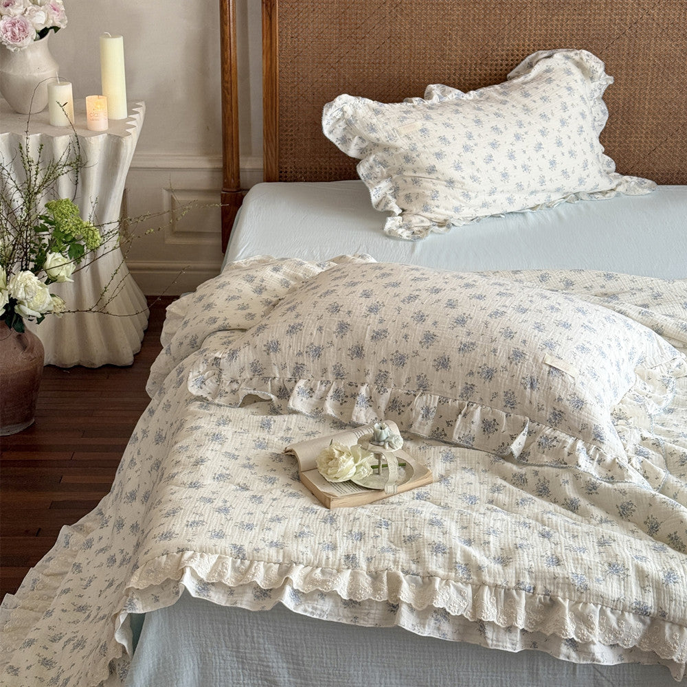 Comforter set styled on bed with ruffle edge and floral pattern