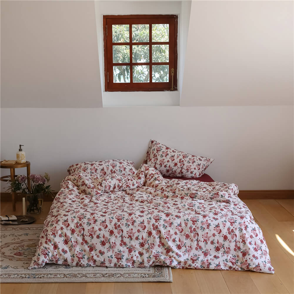 Complete view of the Rose Knit Cotton Bedding Set on a bed, set against a bright, vintage attic window.