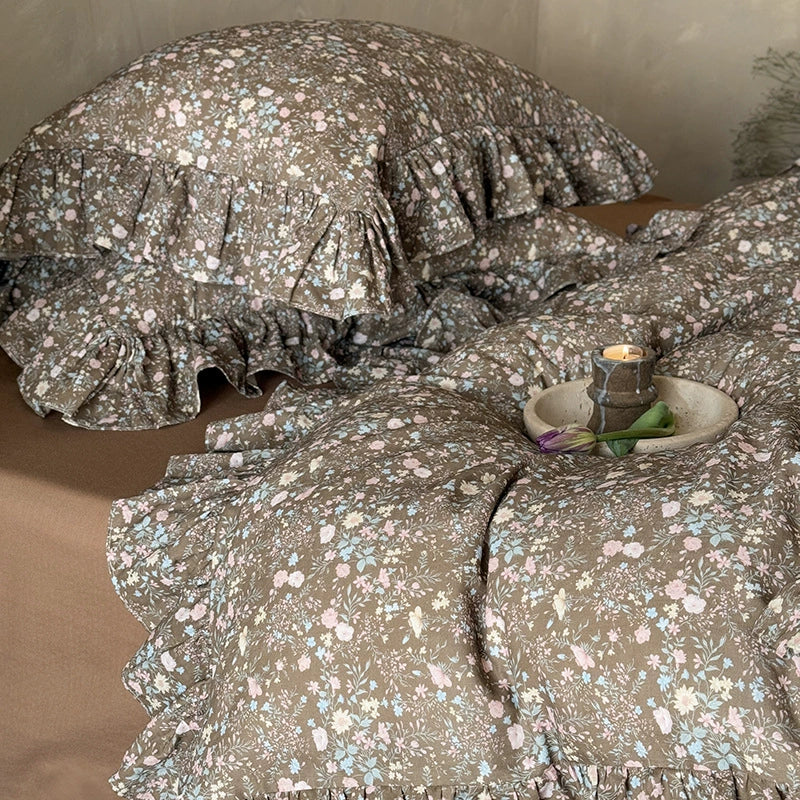 Close-up of the vintage bloom bedding set (duvet and stacked pillows), focusing on the ruffled edges and a small candle setting.