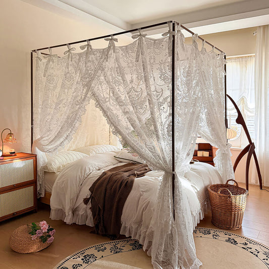 Bedroom with a canopy bed featuring lace curtains, nightstands, and decorative items.