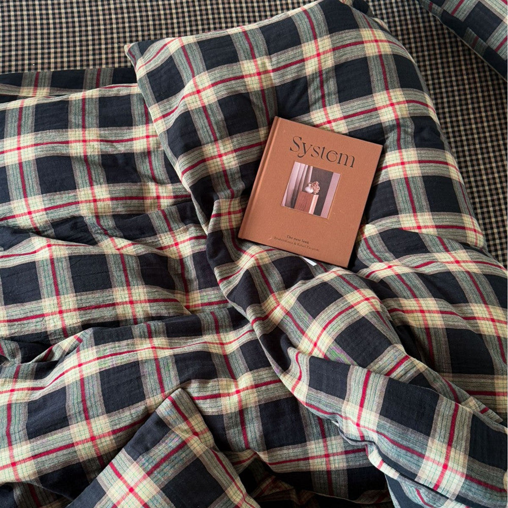 Top-down view of the vintage plaid cotton muslin bedding with a magazine on top, showcasing the high-quality, textured, and rustic aesthetic of the material.