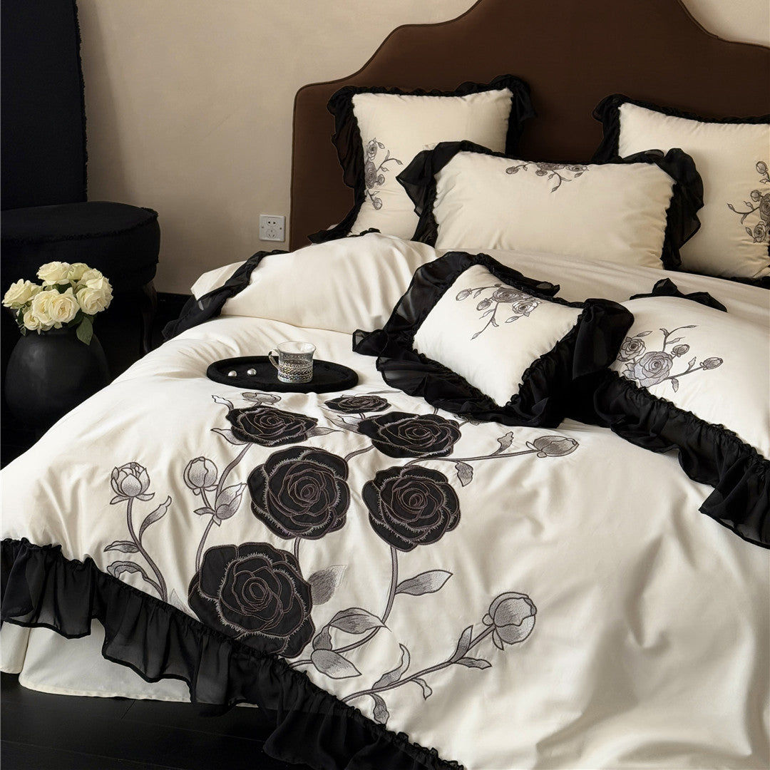 Close-up of black rose embroidery on ivory cotton bedding