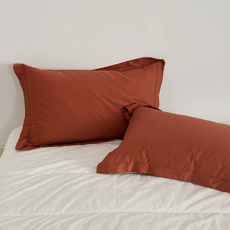 Two Rust-colored pillows from the Brushed Cotton Duvet Cover Set on a white bed, featuring the Soft & Cozy Bedding.
