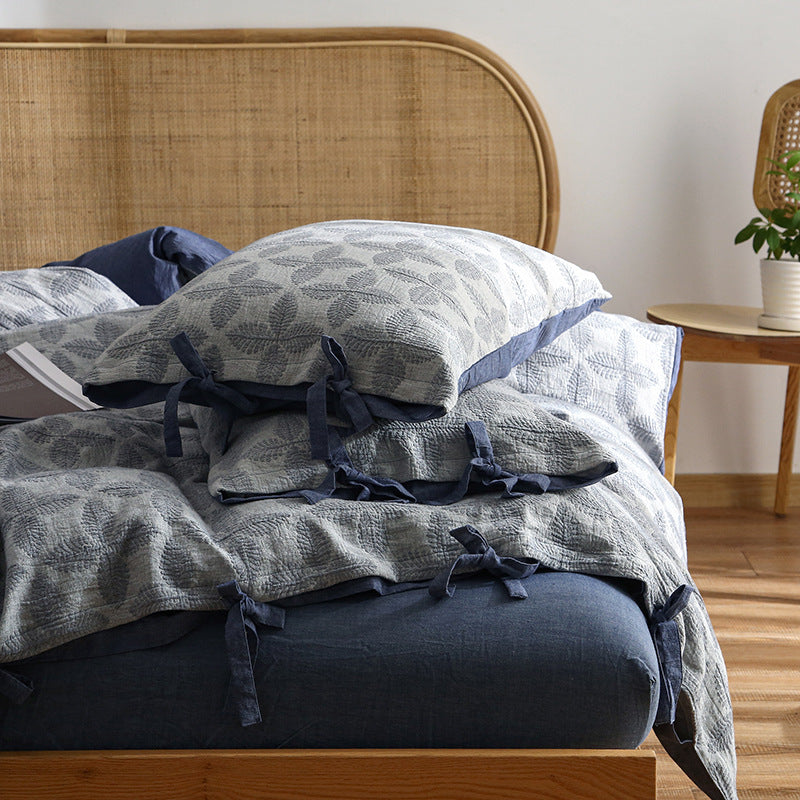 Close-up of Jacquard Cotton Duvet Cover Set in navy and grey, showing tie closure detail and leaf pattern.