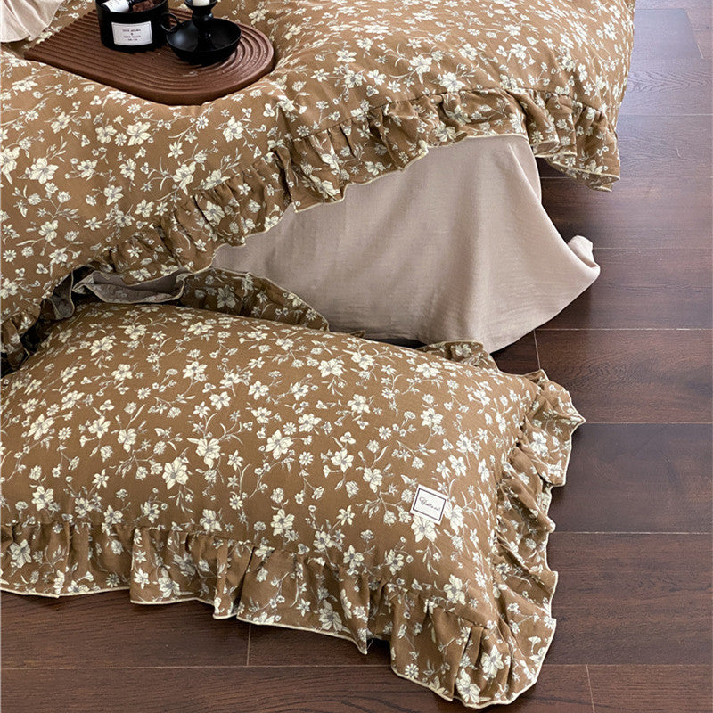 Cozy Earth Tone Bedding: Ruffled floral pillows and duvet shown on a dark wood floor, showcasing the cotton muslin texture.