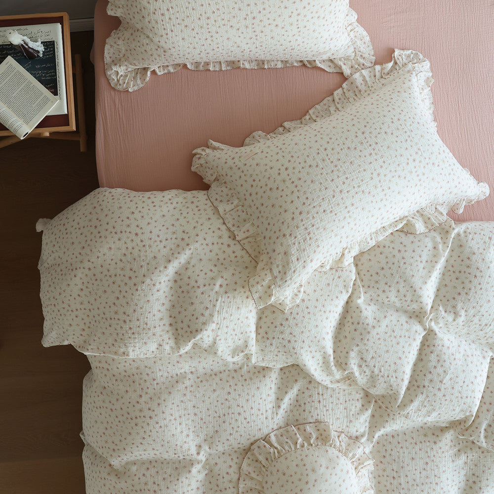 Ditsy floral cotton gauze duvet cover set with ruffles on a bed with a solid pink sheet.