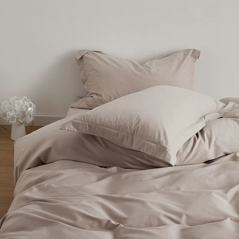 A light grey brushed cotton duvet cover set on a bed, including a duvet cover, flat sheet, and pillowcases.