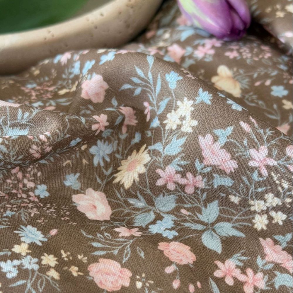 Detailed fabric macro shot of the cotton muslin material, clearly showing the earthy floral pattern with small pink, blue, and white flowers.