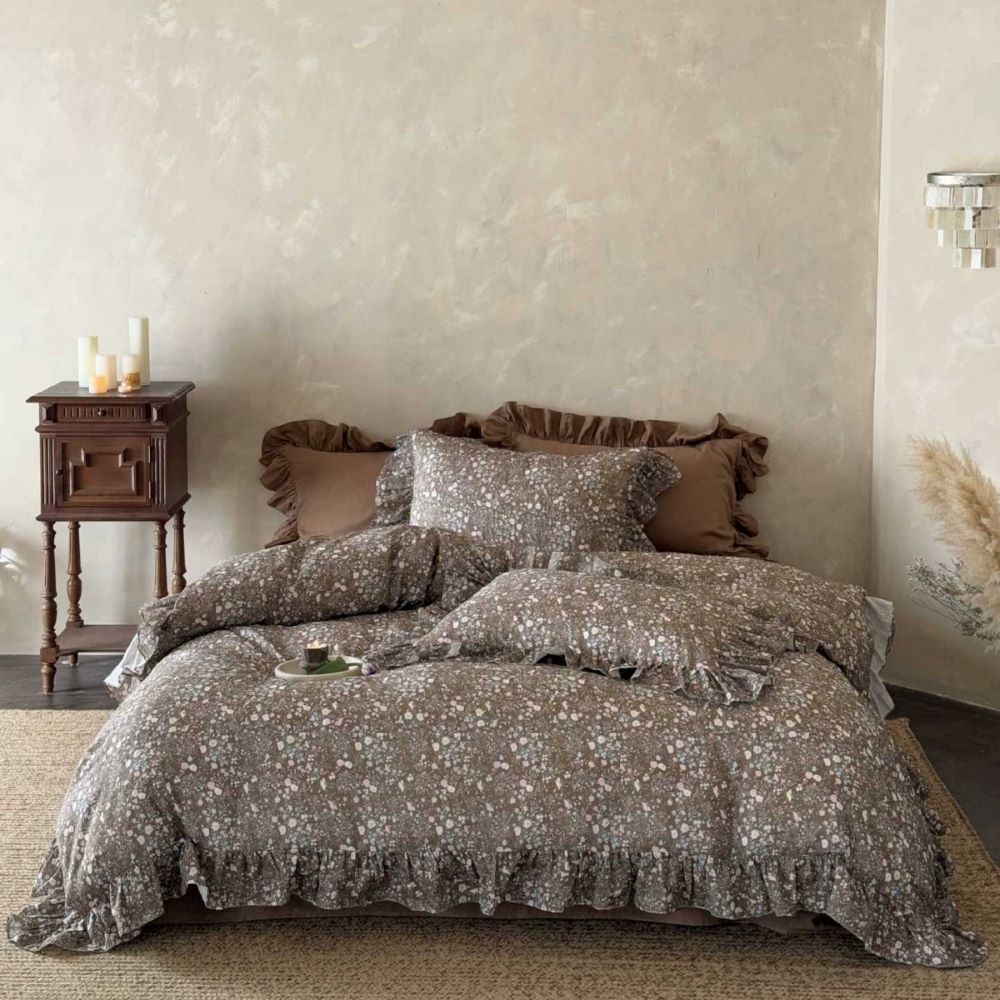 Full view of the bed featuring the ruffled cotton muslin duvet and shams in a rustic, earth-tone bedroom setting.