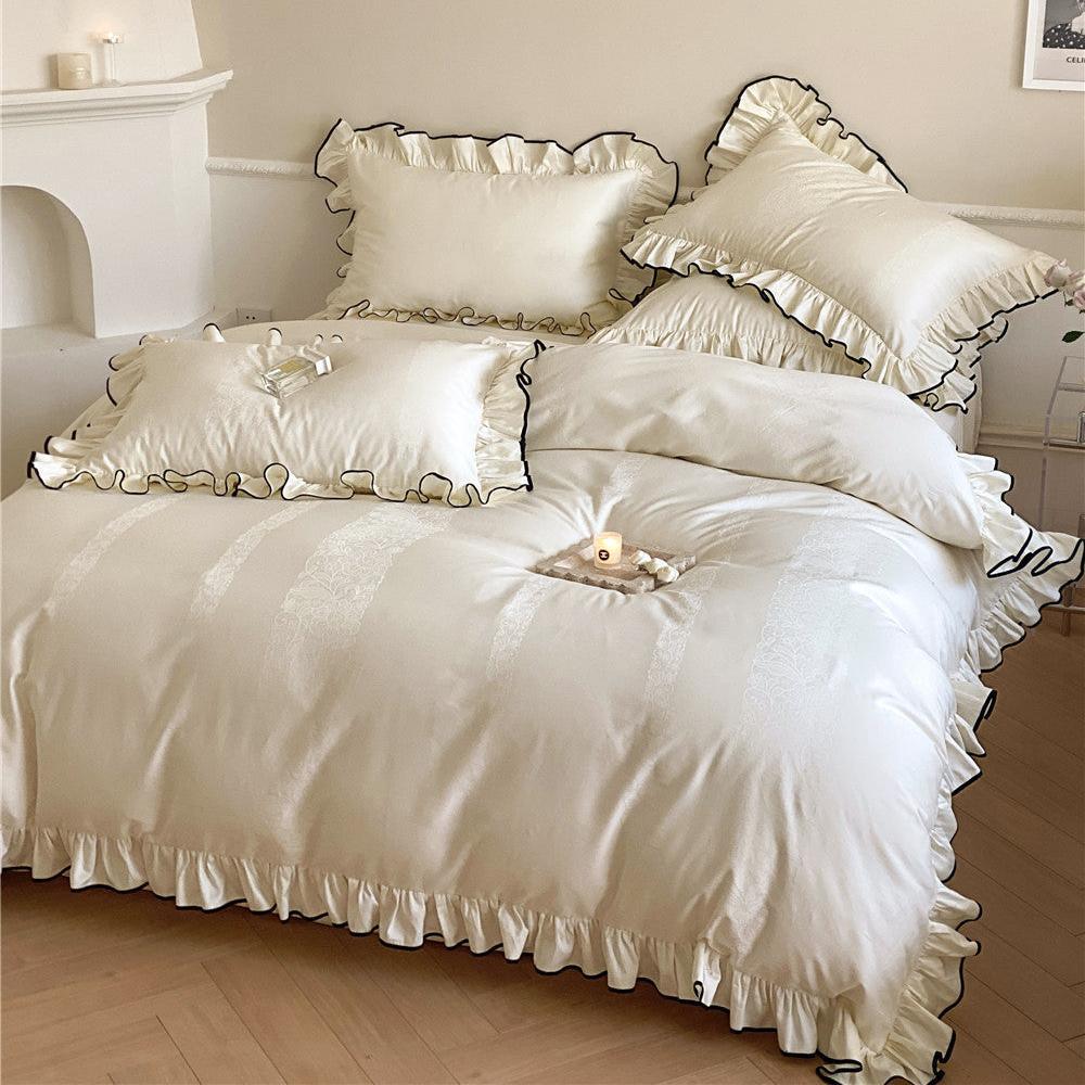 Full bed view of the elegant ruffle bedding set in cream white, showcasing the satin sateen fabric and multiple pillows with a delicate lace pattern.