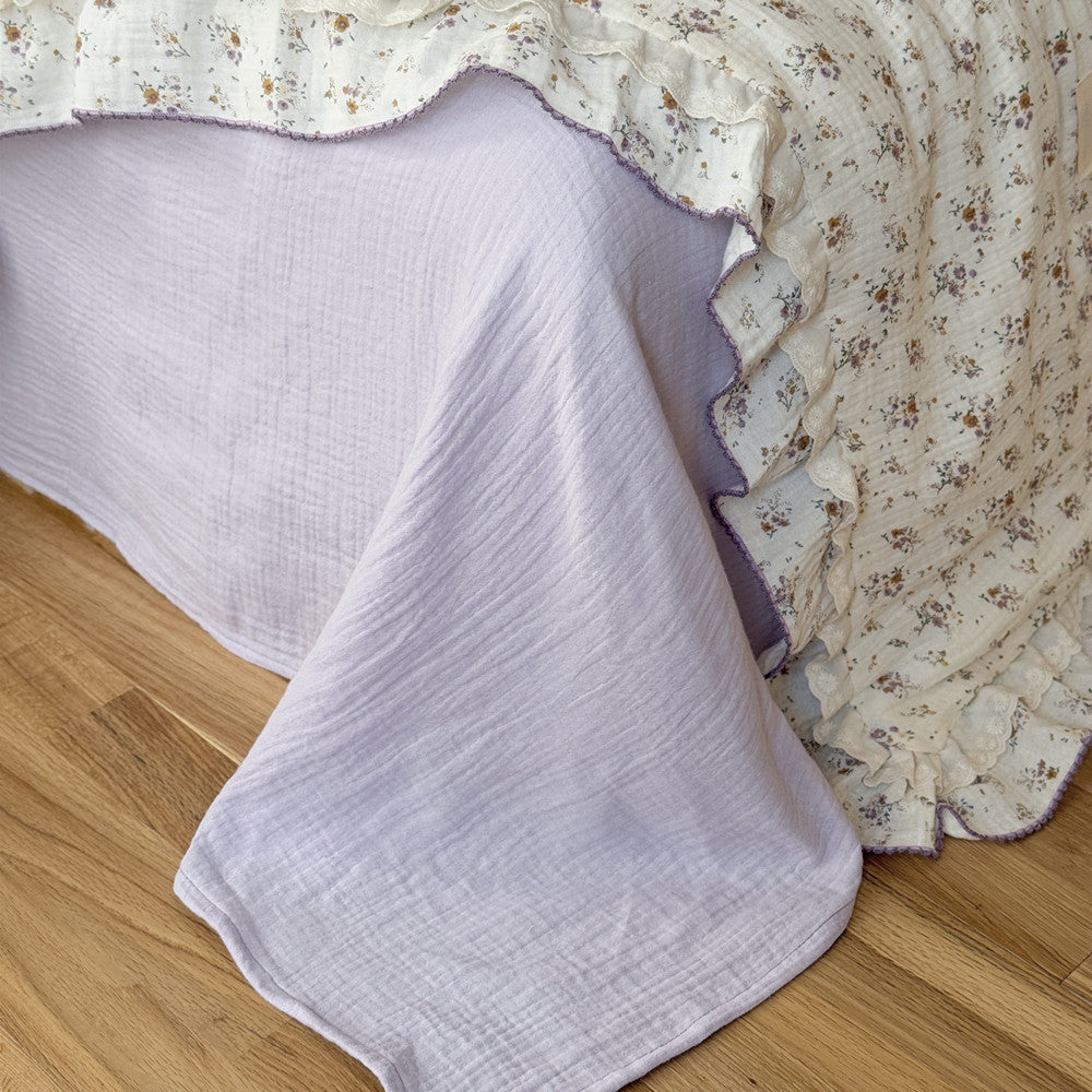 Romantic floral cotton comforter with yellow print and lavender ruffled trim on bed