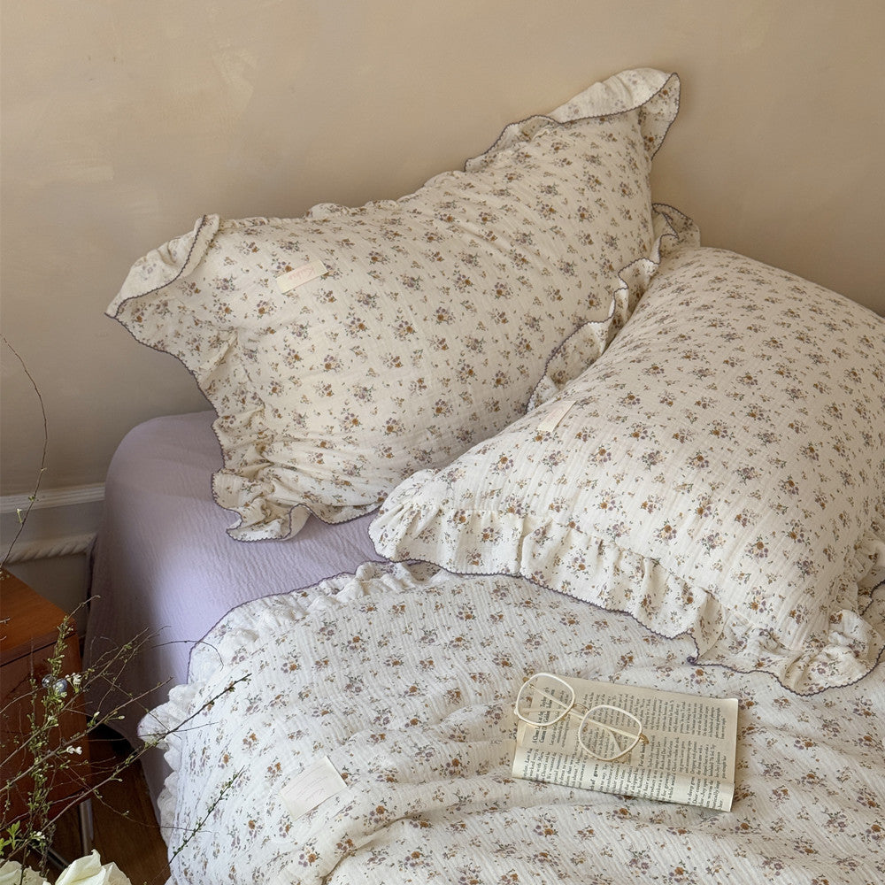 Elegant floral comforter with lavender trim and pillow styling in cozy bedroom