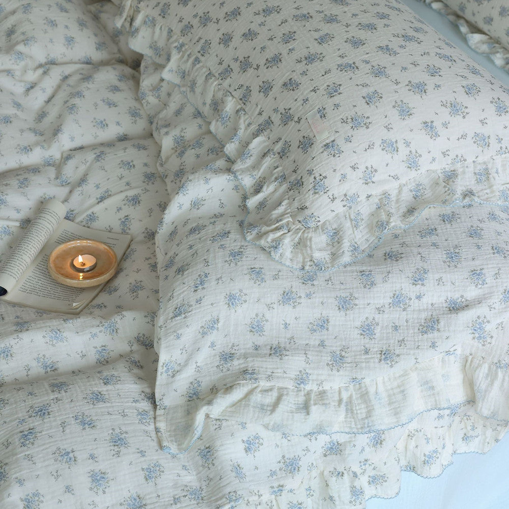 A close-up shot of a blue floral cotton muslin bedding set, showing the soft texture and detailed blue flower print.